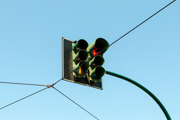 Traffic lights suspended above a road junction, blue sky background.