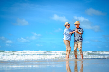 Plan life insurance of happy retirement concepts. Senior couple dancing at the beach looking the ocean on a good day in sunny day morning.