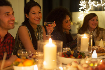 Smiling friends drinking champagne at candlelight Christmas dinner