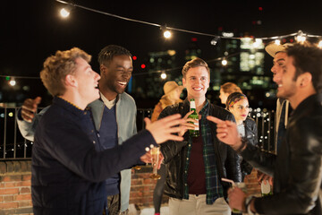 Young men drinking and laughing at rooftop party