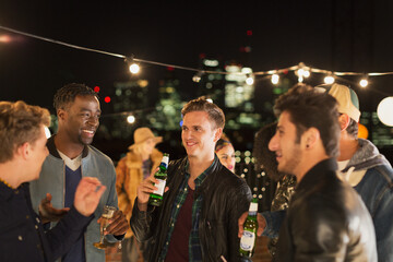 Young men drinking beer and talking at rooftop party