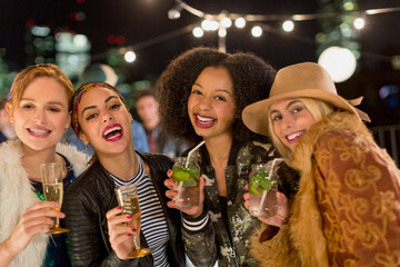 Portrait enthusiastic young women drinking cocktails at party