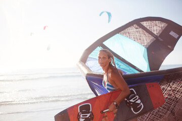 Portrait woman carrying kiteboard equipment on beach