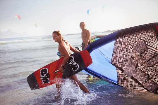 Couple pulling kiteboarding equipment into ocean surf