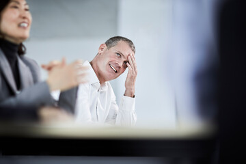 Smiling businessman with head in hands in meeting