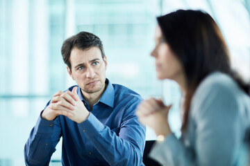 Attentive serious businessman listening to businesswoman in meeting