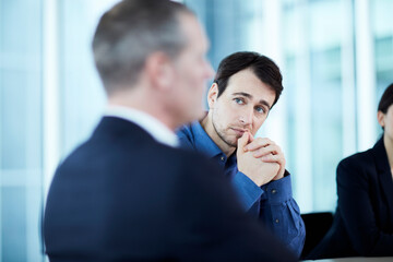 Attentive serious businessman listening to colleague in meeting