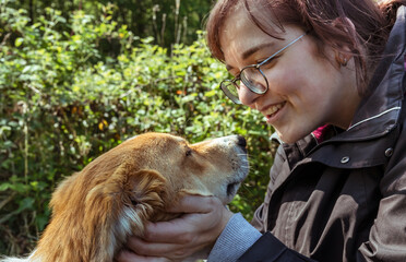 Young smiling woman speakind with her pet dog outdoors