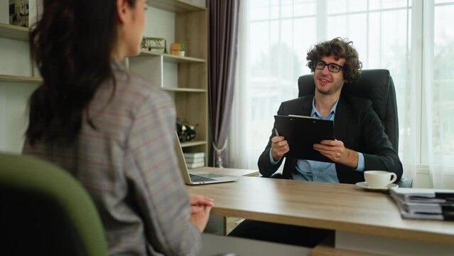 job interview and new work concept.businessman HR manager interviewing woman.Candidate female sitting her back to camera,Happy recruiter doing handshake with candidate after job interview at office