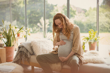 Smiling pregnant woman holding stomach