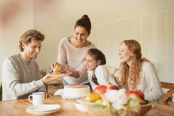 Woman serving cake to family at dining table