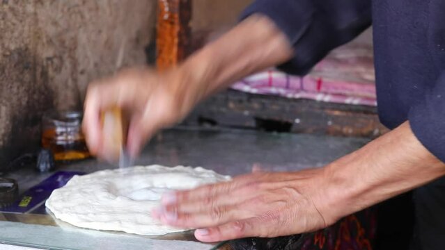 The baker applies a pattern to the dough for Uzbek flatbread