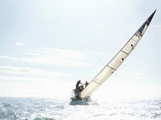 Obraz premium Sailboat tilting on sunny ocean