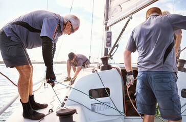 Men sailing adjusting sailboat rigging