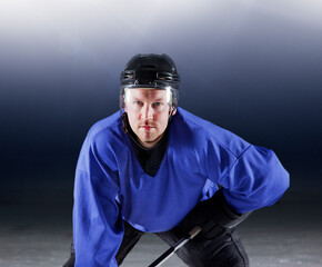 Portrait determined hockey player in blue uniform on ice