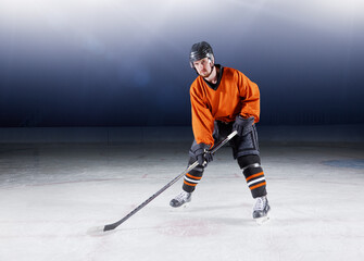 Portrait confident hockey player in orange uniform on ice