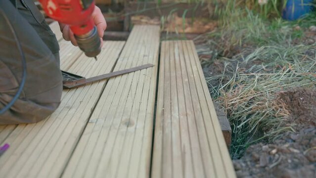 Male builder using drill to unscrew the screws  off the timber