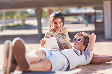 Teenage couple hanging out using digital tablet