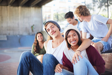 Portrait smiling teenage couple hanging out with friends at skate park