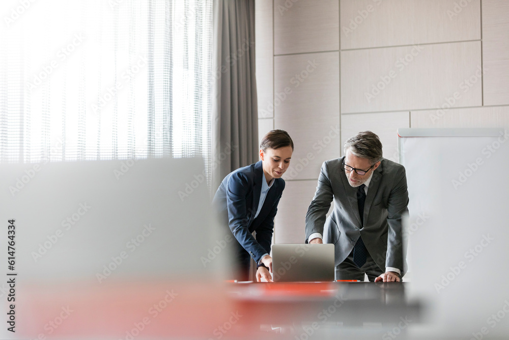 Poster Businessman and businesswoman using laptop in conference room