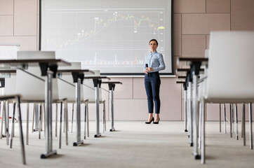 Portrait confident businesswoman microphone at projection screen chart in conference room