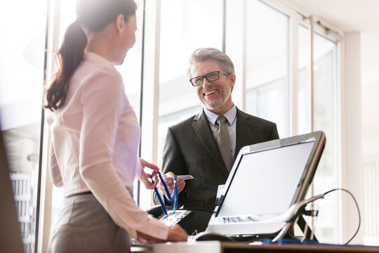Businessman showing credentials to businesswoman at front desk