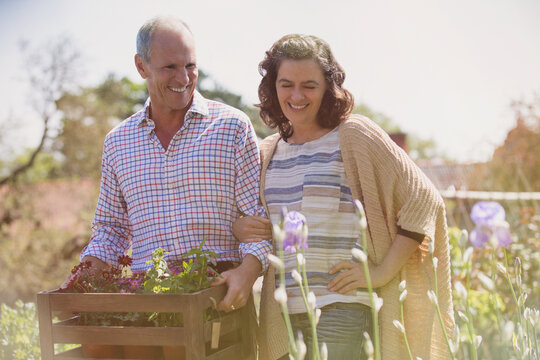 Smiling couple shopping for flowers in sunny plant nursery garden