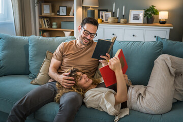 man and woman caucasian adult couple read books at home on sofa bed