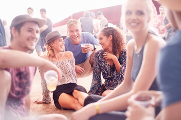 Young friends hanging out drinking beer and talking at music festival