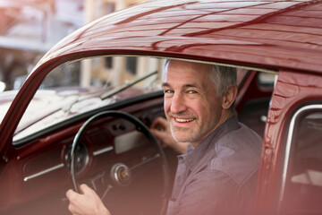 Portrait smiling mechanic inside classic car - obrazy, fototapety, plakaty