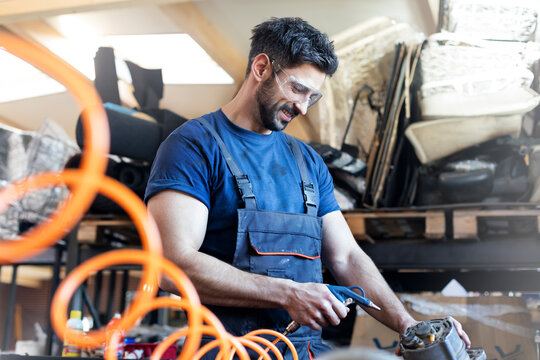 Smiling metal worker using equipment in workshop