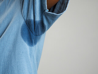 Sweating, wet armpits on a man with a bad body odor or foul odor use of deodorant