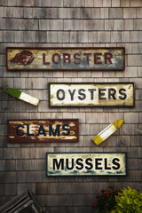 Old seafood name product signs on a wooden shingle wall - 614768578