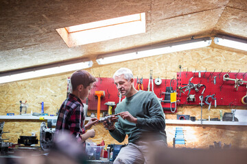 Father explaining tool to son in auto repair shop