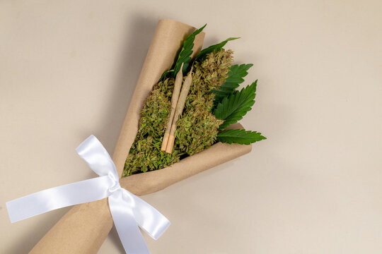 A bouquet of cannabis flowers and weed joints with a white ribbon tied to the handle