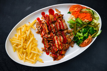 Fried meat with french fries and a salad of pickled cucumbers, tomatoes, carrots, lettuce, parsley and ketchup, shawarma without lavash.