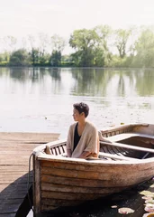 Foto op Canvas Serene woman sitting in canoe at sunny lakeside dock © KOTO