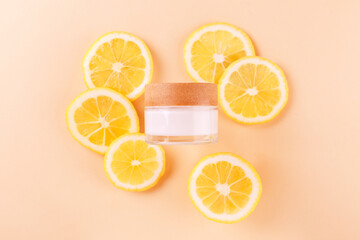 Citrus fruit glass jar of cream moisturizer and orange lemon slices on beige background. Flat lay, top view. skin care routine.