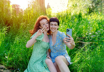 two friend, girlfriend and women using a mobile phone, camera and taking selfie in public park. Romantic concept