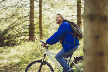 Obraz premium Smiling man riding mountain biking in woods