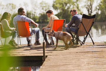 Friends and dog at sunny lakeside dock