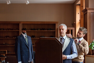 Tailor fitting businessman for suit in menswear shop