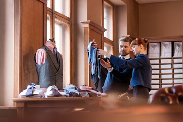 Worker showing ties to businessman in menswear shop