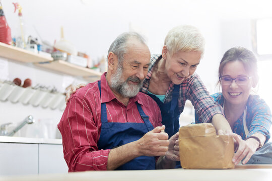 Friends cutting block of clay in pottery studio