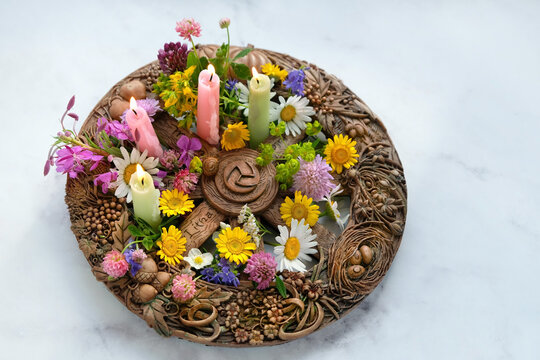 Altar for Summer solstice, Litha wiccan holiday. wheel of the year with colorful flowers and candles close up on abstract marble background. symbol of celtic wiccan sabbath, summer season. top view