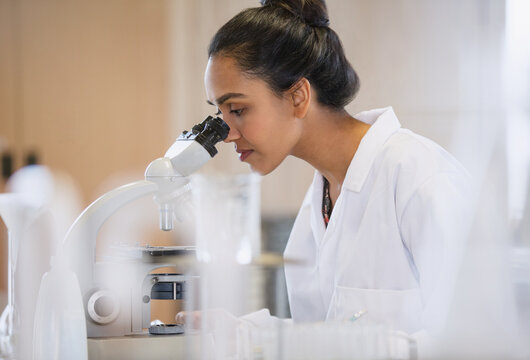 Female scientist using microscope in laboratory - Powered by Adobe
