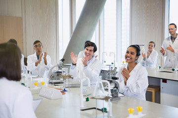 College students clapping for classmate in science laboratory classroom