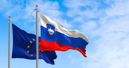 The flags of Slovenia and the European Union waving in the wind on a clear day
