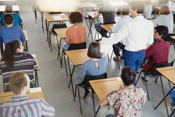 Professor collecting test from students in classroom