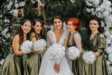 Bridesmaids smiling together with the bride. The bride and her fun friends celebrate the wedding after the ceremony in matching dresses. Bride and friends in nature